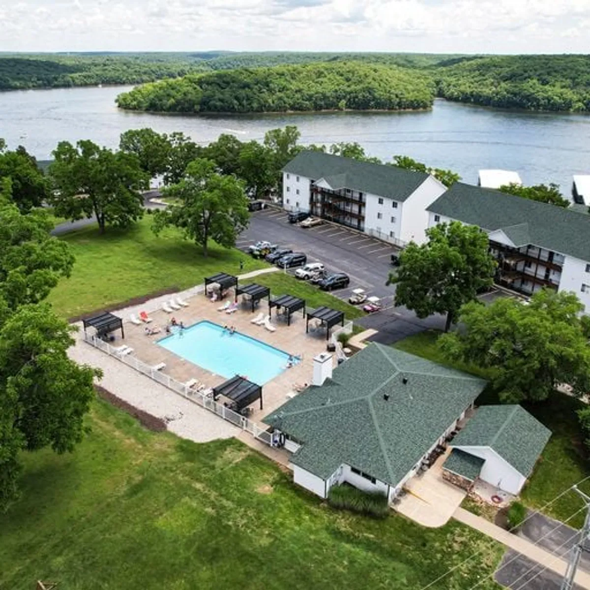 An inviting outdoor swimming pool is surrounded by lush greenery, with lounge chairs arranged for relaxation and a view toward the waterfront. The pool area is spacious, perfect for group gatherings or unwinding after a day of adventure.