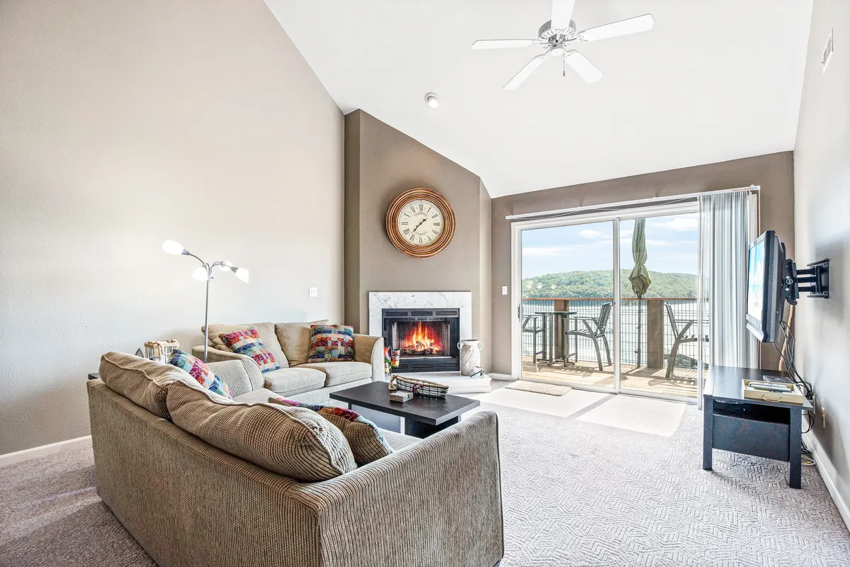 A cozy clubhouse interior featuring a fireplace, large window with a scenic view, and comfortable seating. The space is perfect for entertaining, hosting game nights, or simply unwinding after a day outdoors.